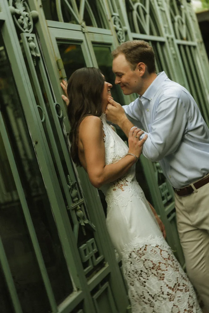 Alexandra and Dalton sharing a kiss beside a green gate