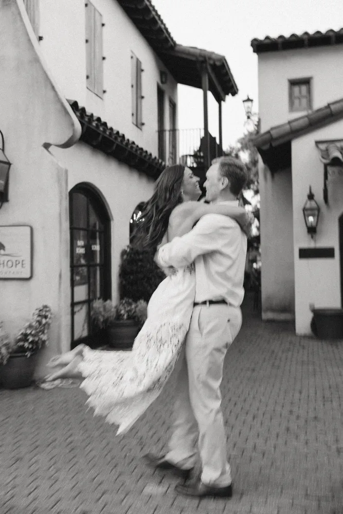 A black-and-white photo of Dalton lifting Alexandra in a courtyard